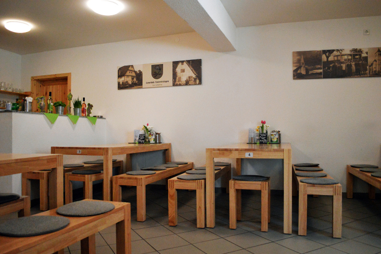 Ein ruhiges Café mit Holztischen und Stühlen, dekoriert mit Blumen und Bildern an der Wand.